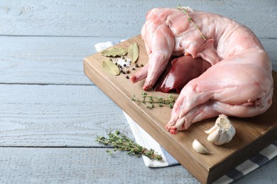 Photo of Whole raw rabbit, liver and spices on grey wooden table, space for text