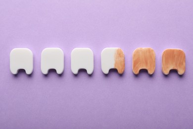 Photo of Clean and dirty plastic teeth on violet background, flat lay