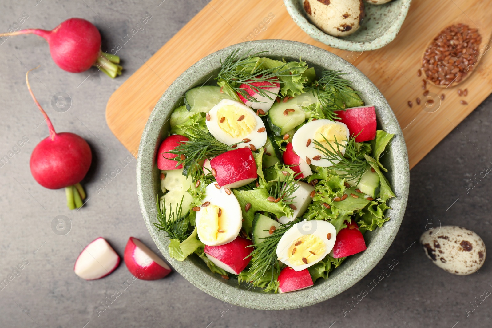 Photo of Delicious radish salad and ingredients on grey table, flat lay