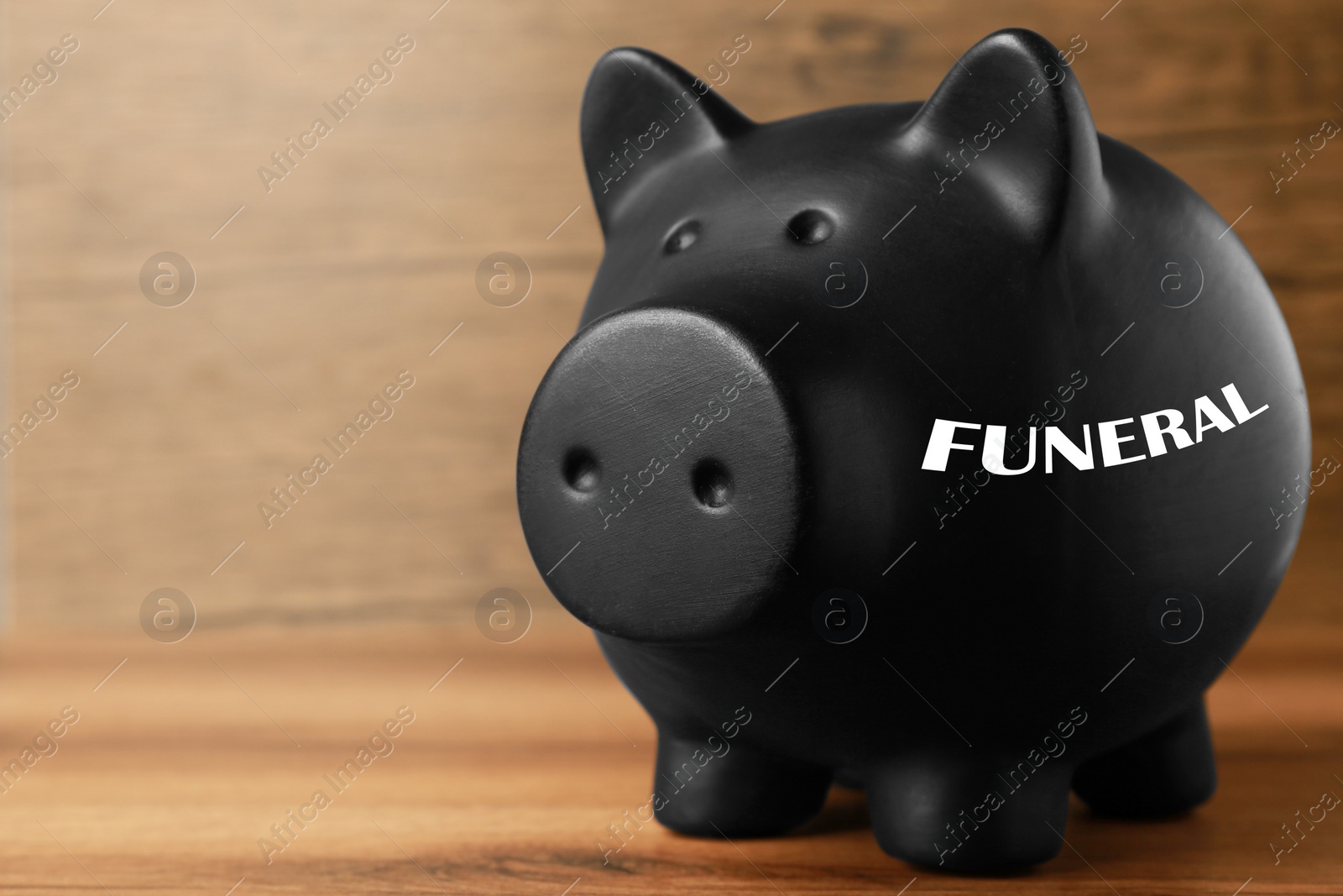 Image of Money for funeral expenses. Black piggy bank on wooden table. Space for text