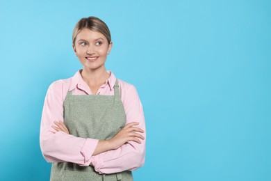 Photo of Beautiful young woman in clean apron with pattern on light blue background. Space for text