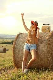 Photo of Happy hippie woman with receiver near hay bale in field