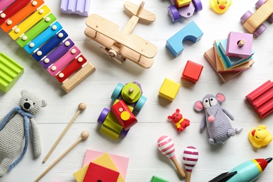 Photo of Different toys on white wooden background, flat lay