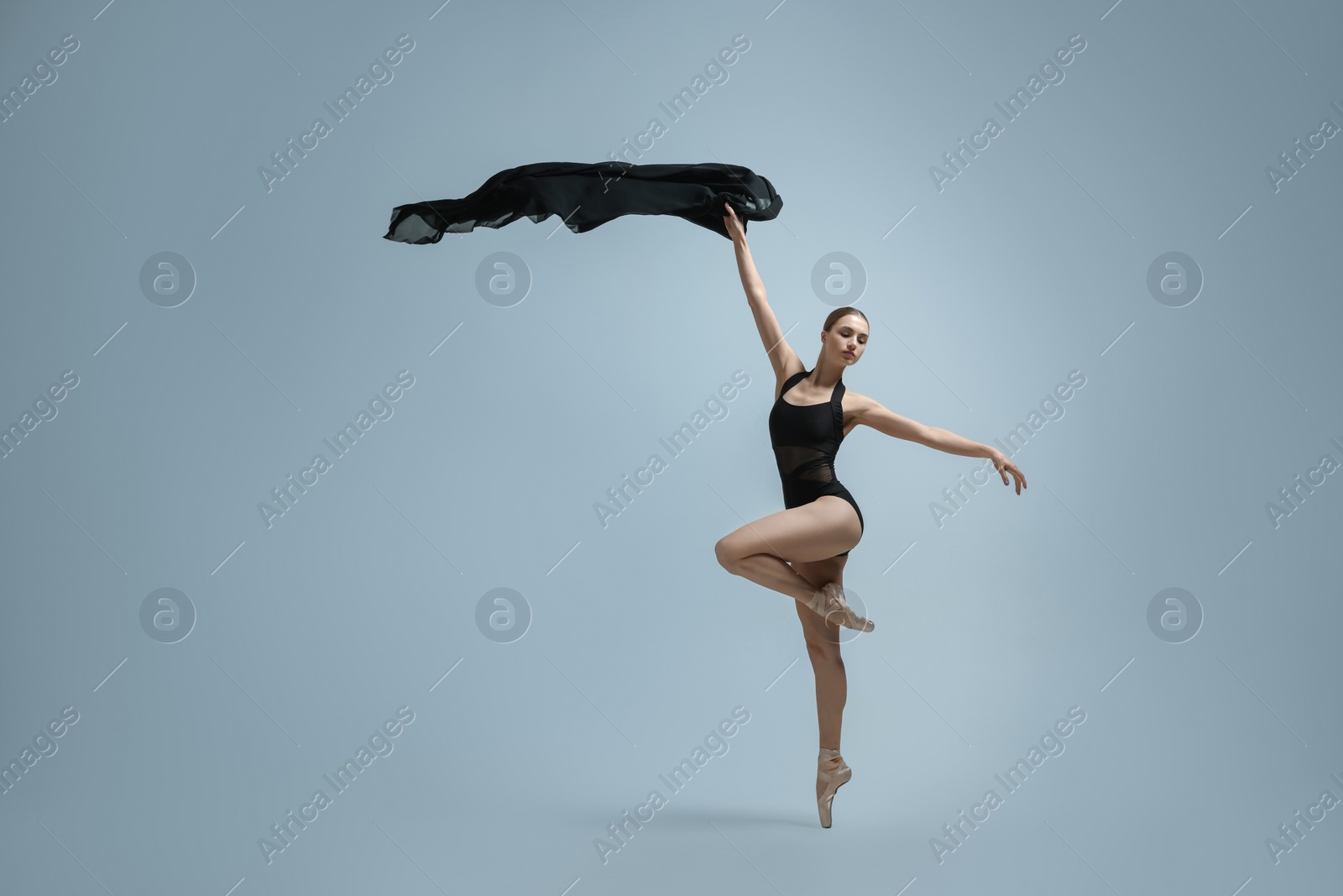 Photo of Graceful young ballerina practicing dance moves with black veil on grey background. Space for text