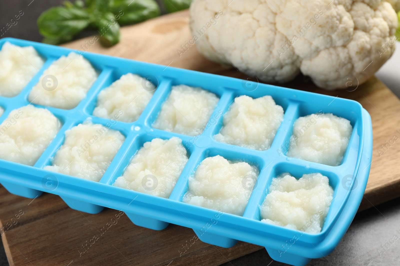 Photo of Cauliflower puree in ice cube tray on grey table, closeup. Ready for freezing