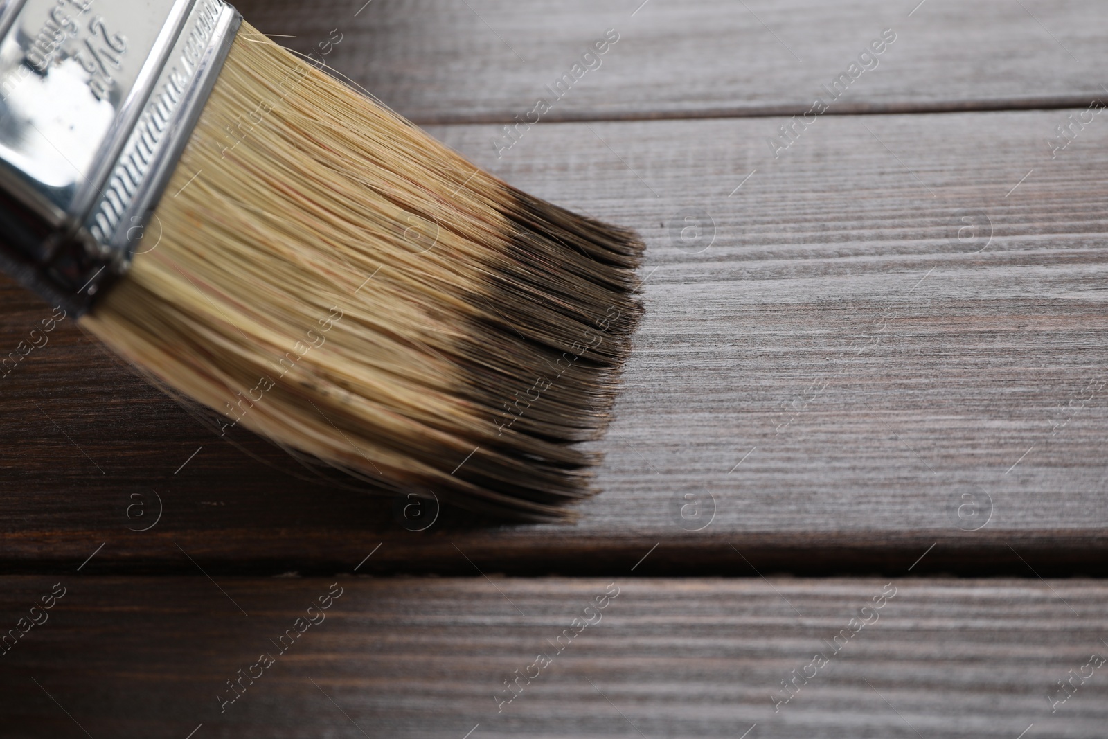 Photo of Applying wood stain with brush onto wooden surface, closeup