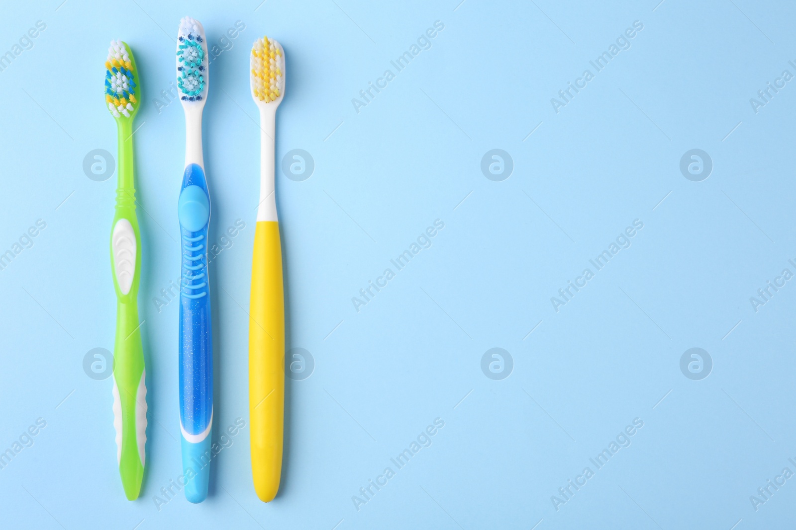 Photo of Many different toothbrushes on light blue background, flat lay. Space for text