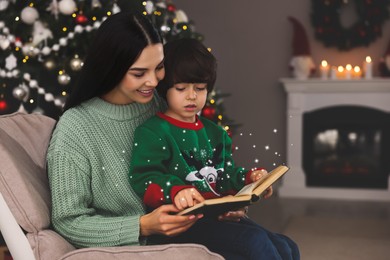 Image of Mother with her cute son reading book in room decorated for Christmas