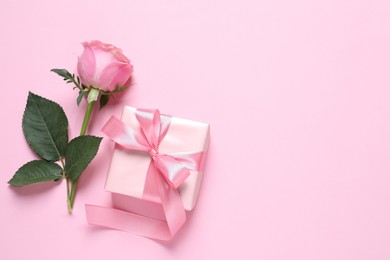 Photo of Gift box and beautiful rose flower on pink background, flat lay. Space for text