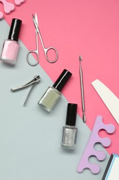 Photo of Nail polishes and set of pedicure tools on color background, flat lay