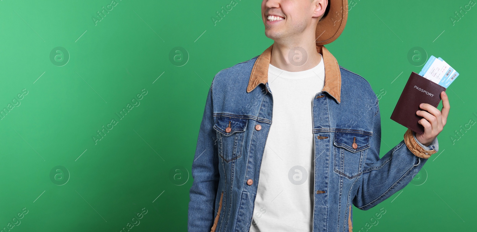 Photo of Smiling man with passport and tickets on green background, closeup. Space for text