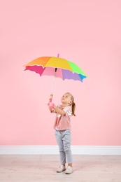 Photo of Little girl with rainbow umbrella near color wall