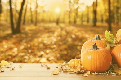 Image of Happy Thanksgiving day. Fresh pumpkins, acorns and fallen leaves on wooden table outdoors, space for text 