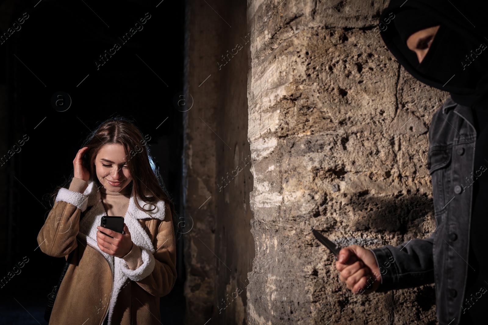 Photo of Criminal with knife hiding behind wall and waiting for victim near alley at night