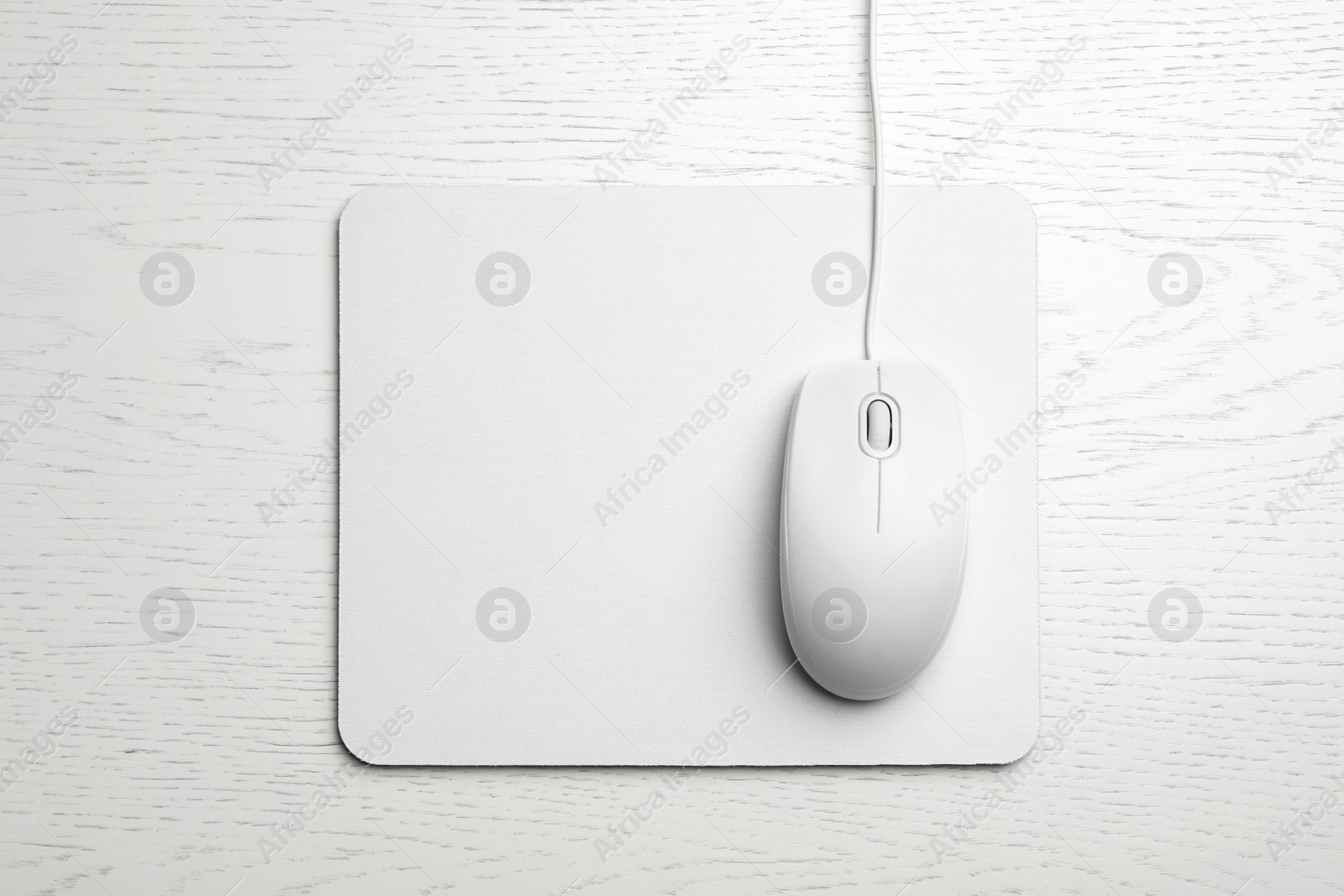 Photo of Wired computer mouse and pad on white wooden background, flat lay. Space for text