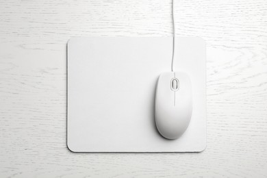 Photo of Wired computer mouse and pad on white wooden background, flat lay. Space for text