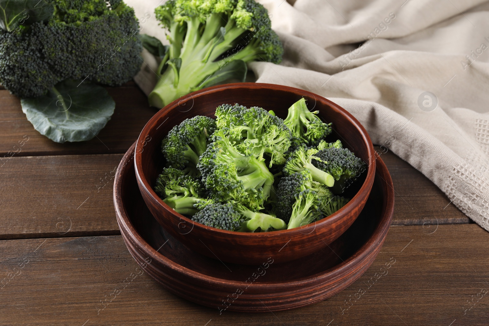 Photo of Bowl with fresh raw broccoli on wooden table