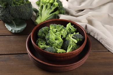 Bowl with fresh raw broccoli on wooden table