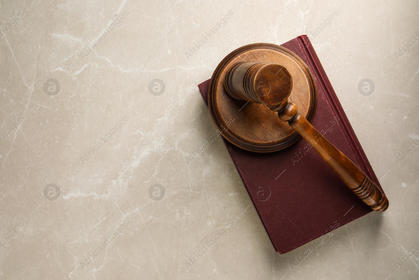 Photo of Wooden gavel, sound block and book on light textured table, top view. Space for text