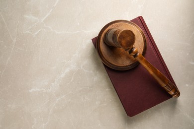 Photo of Wooden gavel, sound block and book on light textured table, top view. Space for text