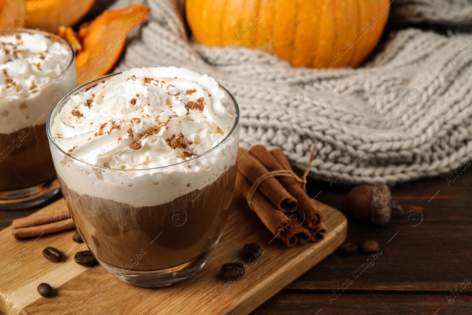 Photo of Glass with tasty pumpkin spice latte on wooden table