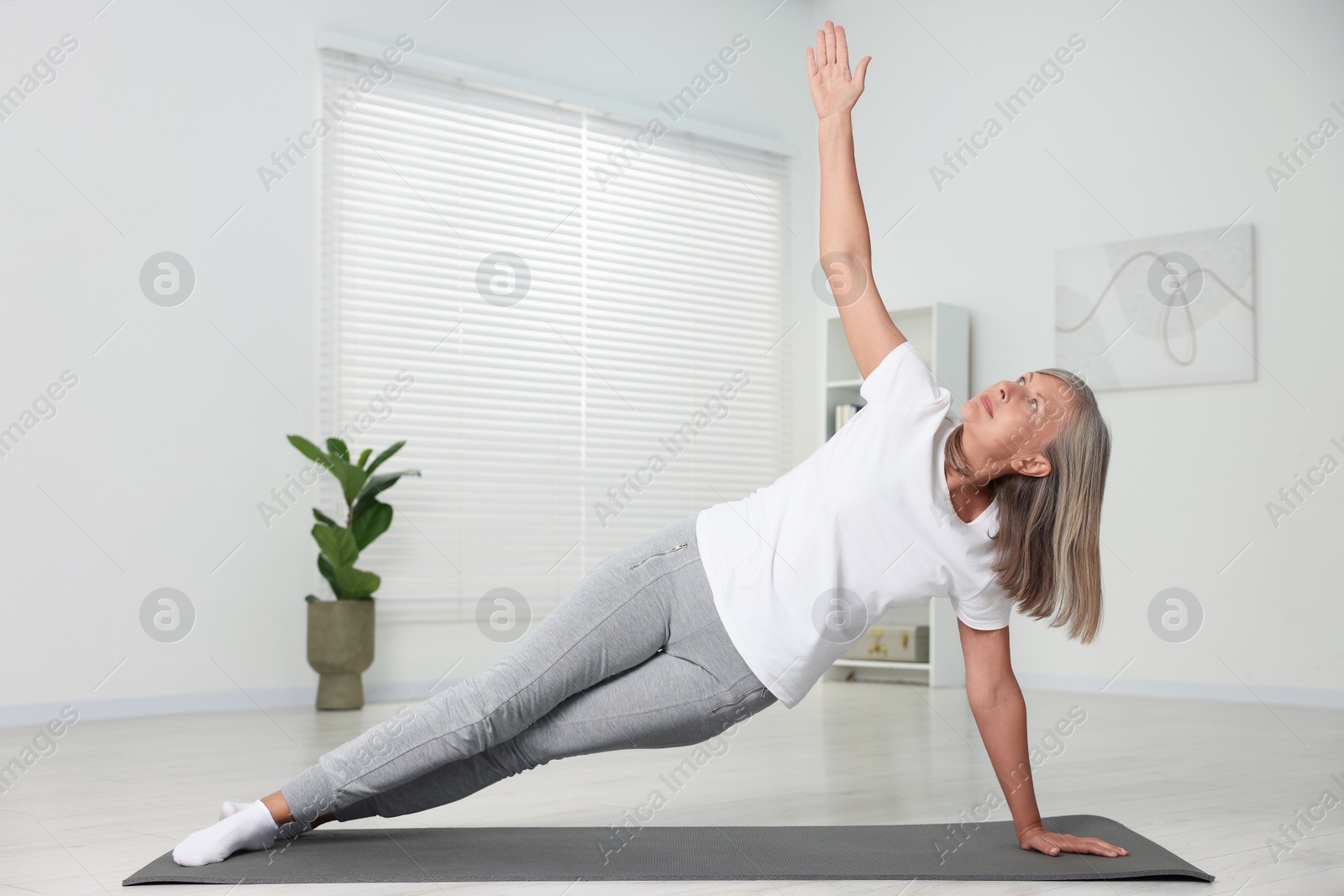 Photo of Senior woman practicing yoga on mat at home