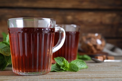 Photo of Cup with hot aromatic mint tea on wooden table, closeup. Space for text