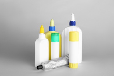 Photo of Different bottles of glue on grey background