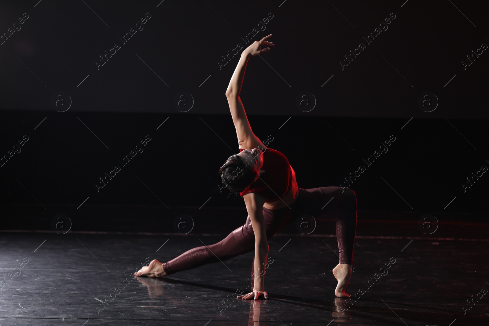 Photo of Young woman performing acrobatic element on stage indoors