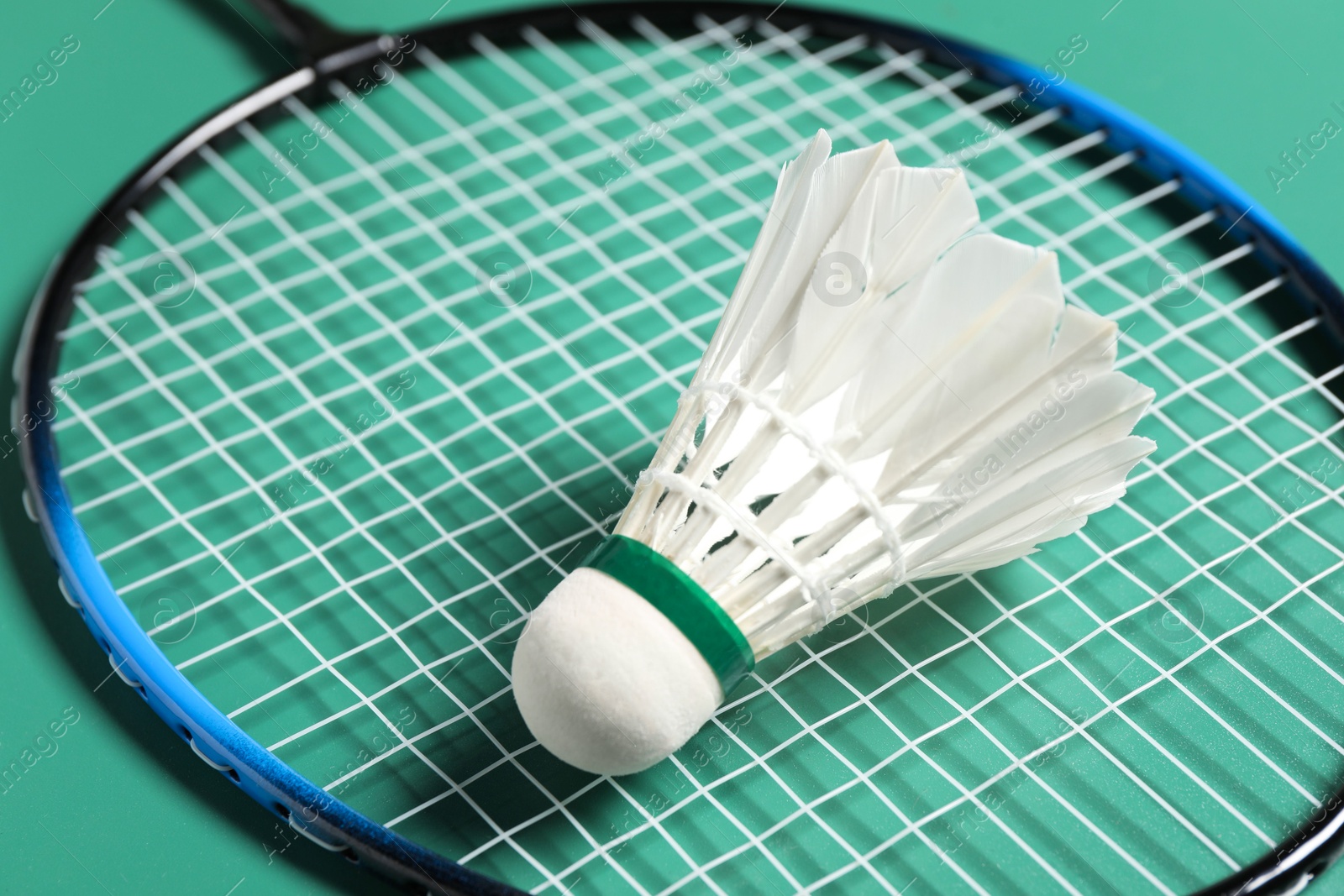 Photo of Feather badminton shuttlecock and racket on green background, closeup