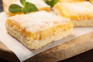 Photo of Tasty lemon bar with powdered sugar and mint on board, closeup