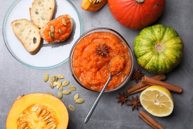 Photo of Delicious pumpkin jam and ingredients on grey table, flat lay