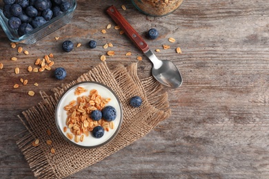 Photo of Glass with yogurt, berries and granola on wooden table, top view