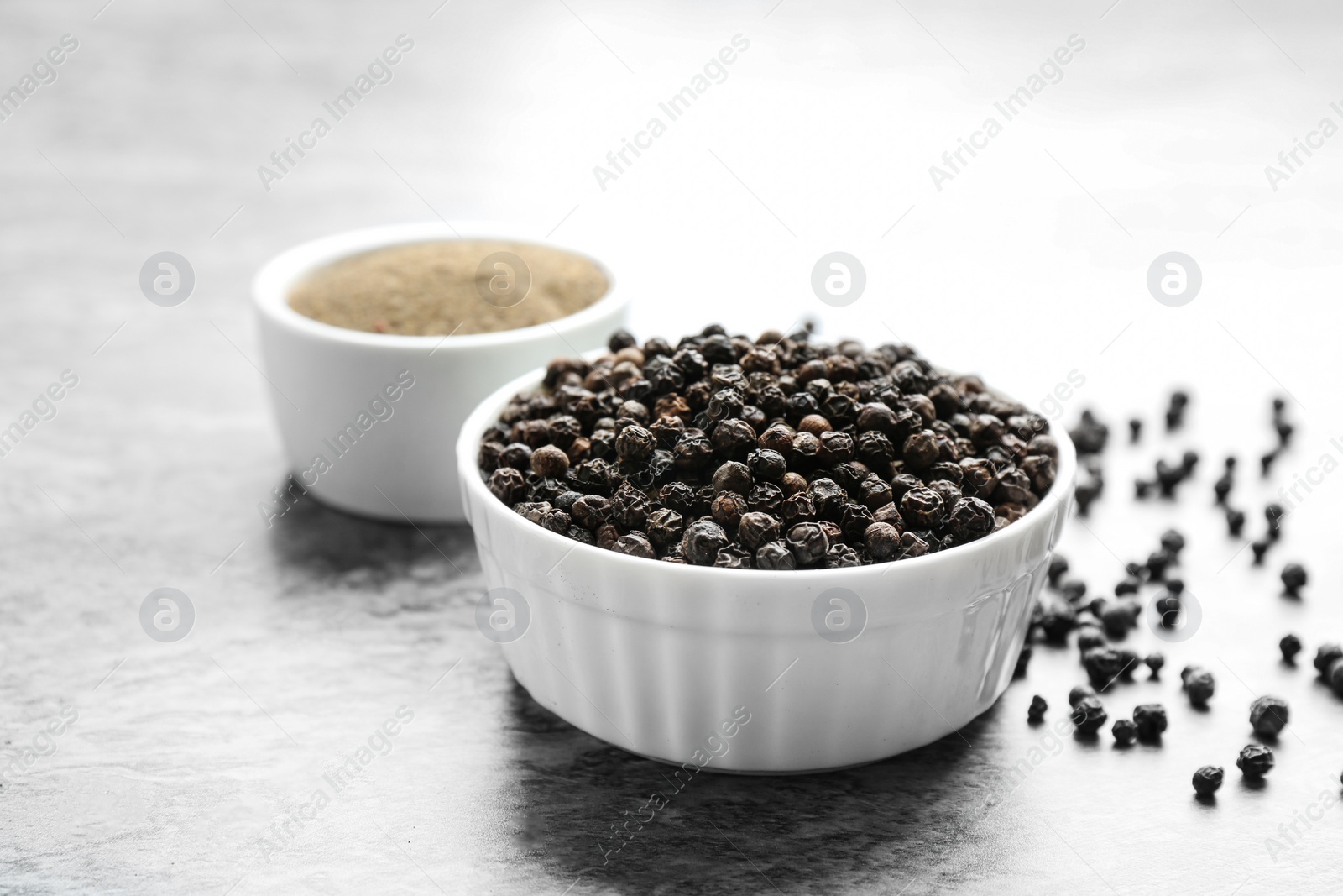 Photo of Ground black pepper and corns on grey table