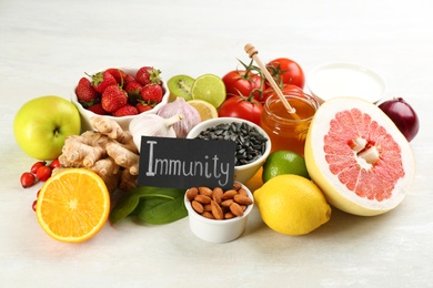 Photo of Card with phrase Immunity and fresh products on light table