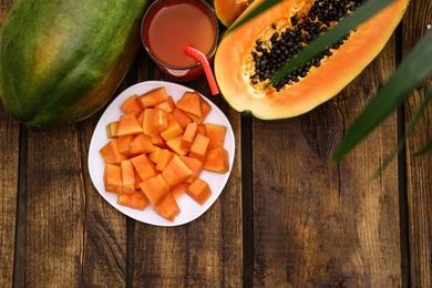 Flat lay composition with fresh juicy papayas on wooden table, space for text