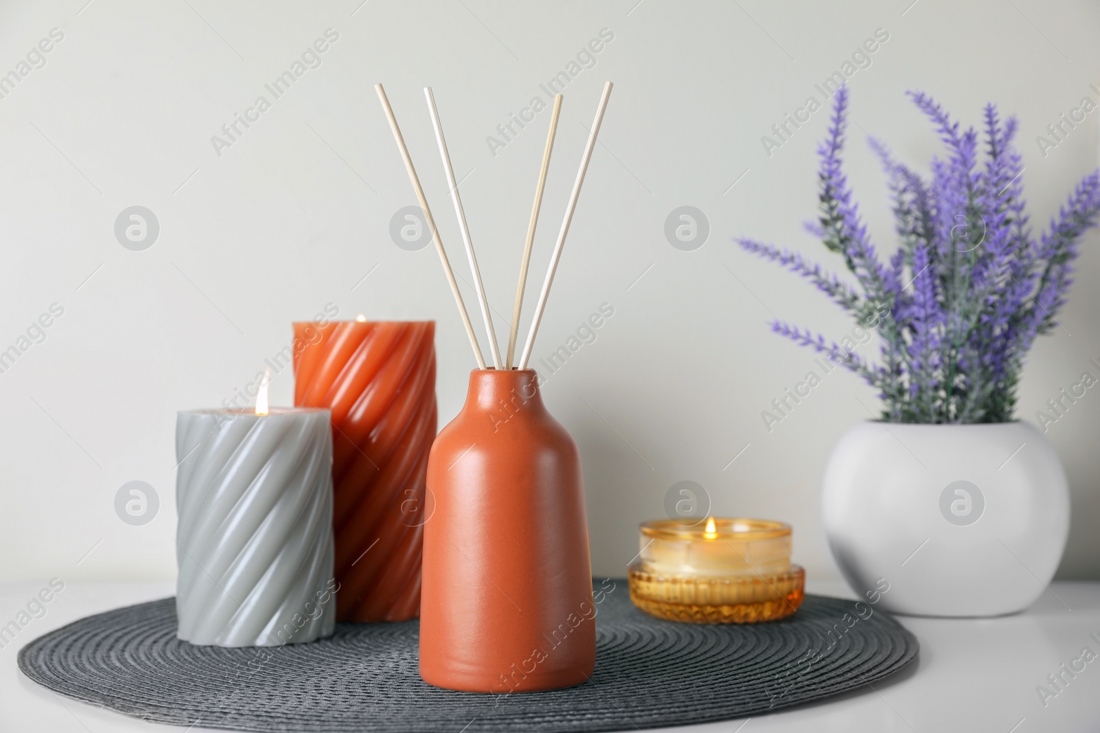 Photo of Aromatic reed air freshener, burning candles and lavender flowers on white table