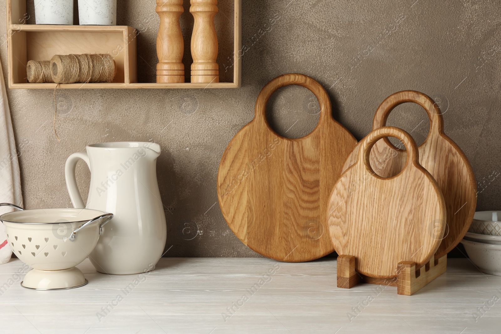 Photo of Wooden cutting boards and kitchen dishware on white table