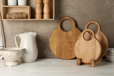 Photo of Wooden cutting boards and kitchen dishware on white table