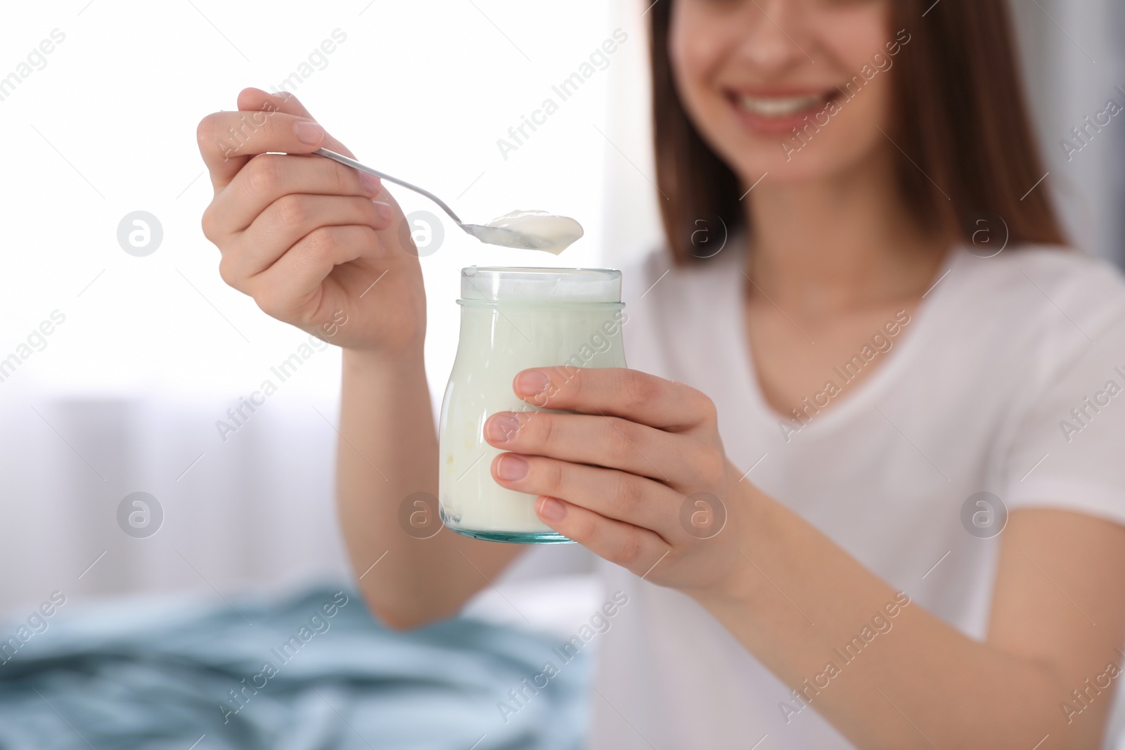 Photo of Young attractive woman with tasty yogurt indoors, closeup