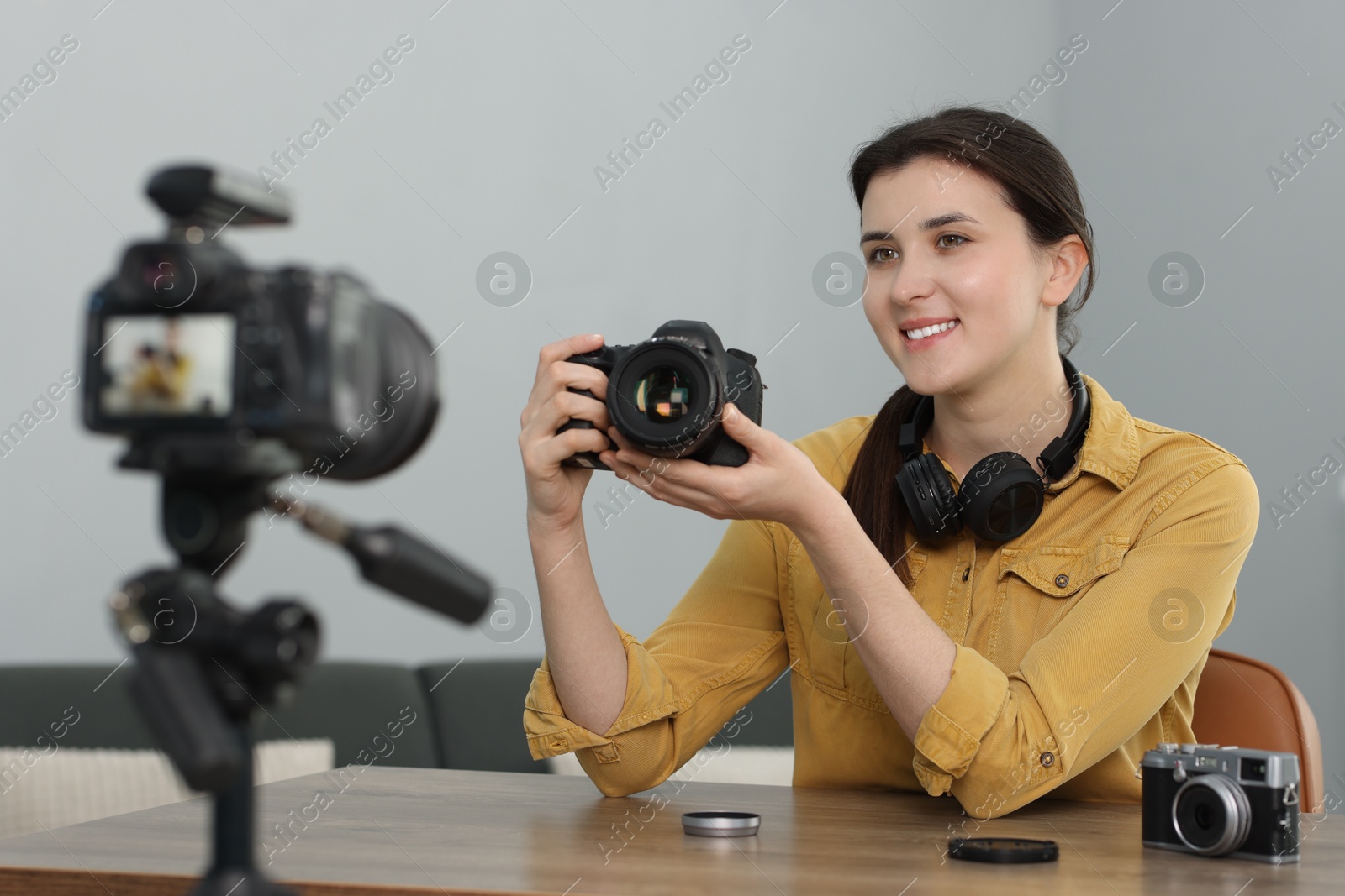 Photo of Smiling technology blogger recording video review about cameras at home