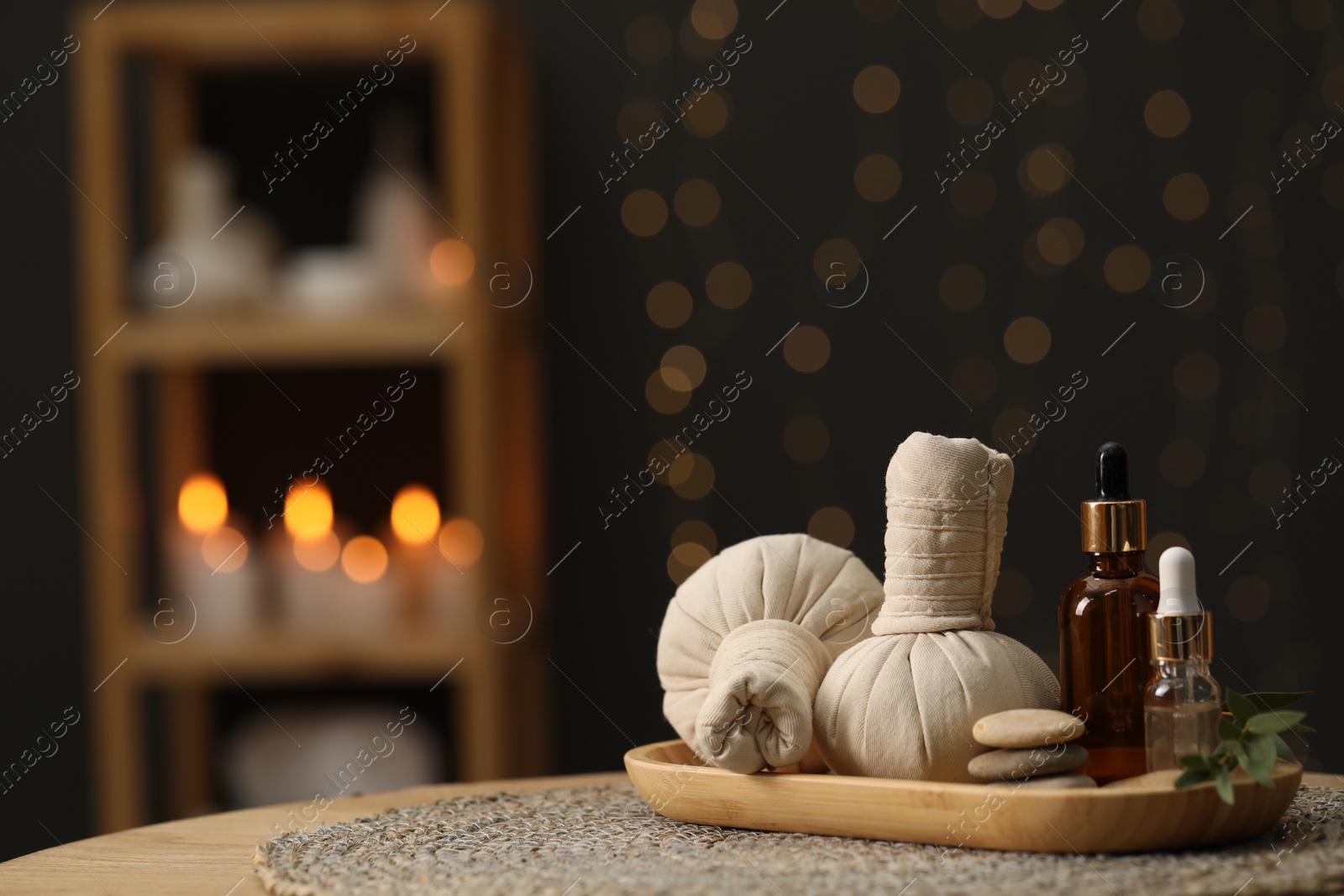 Photo of Spa composition. Herbal sacks, cosmetic products and stones on table indoors. Space for text