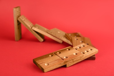 Photo of Wooden domino tiles falling on red background