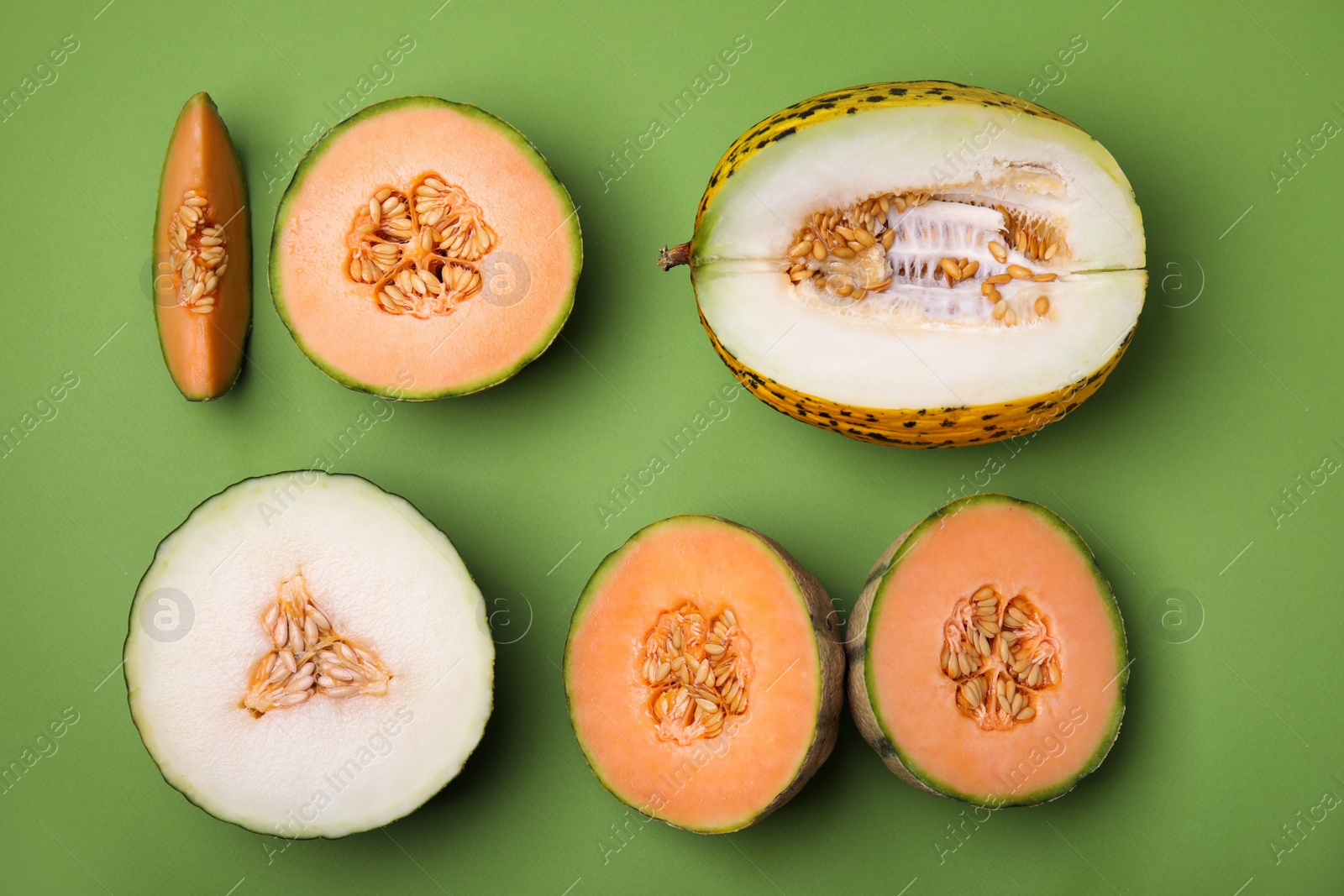 Photo of Cut different types of melons on green background, flat lay