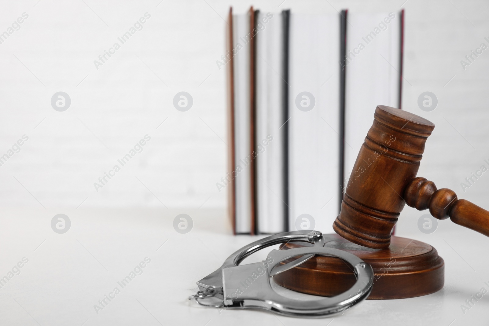 Photo of Gavel, handcuffs and books on table against white background, space for text. Criminal law