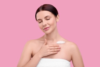Photo of Beautiful woman with smear of body cream on her collarbone against pink background