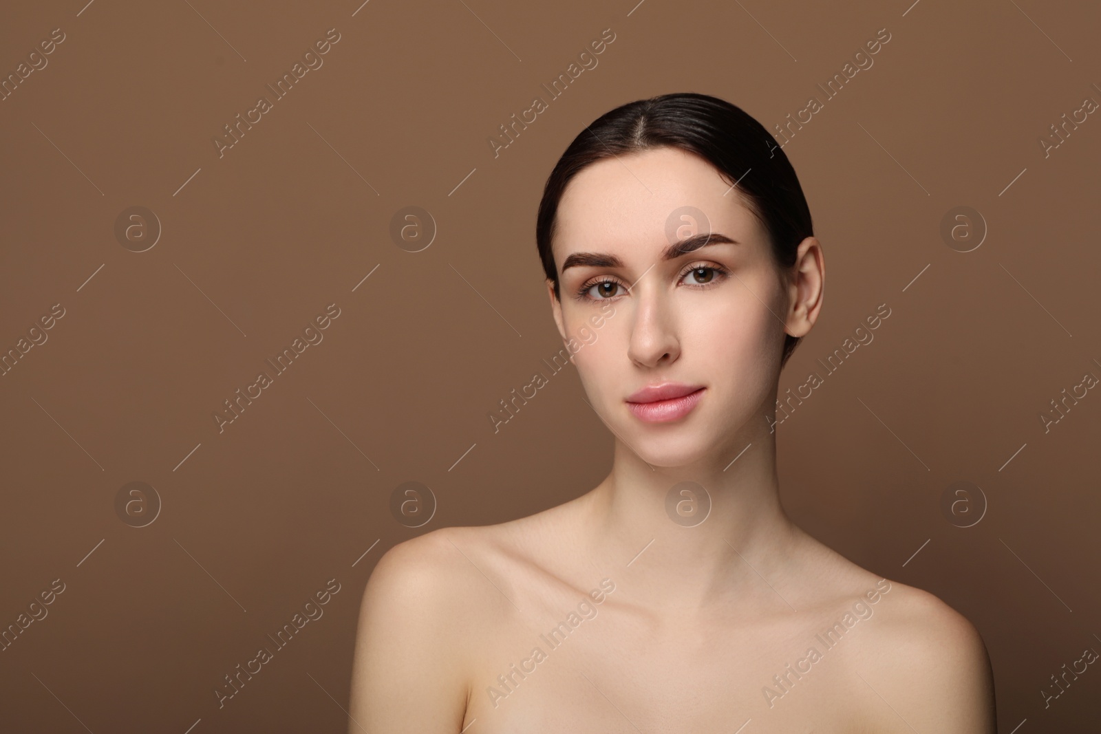 Photo of Portrait of beautiful young woman on brown background. Space for text