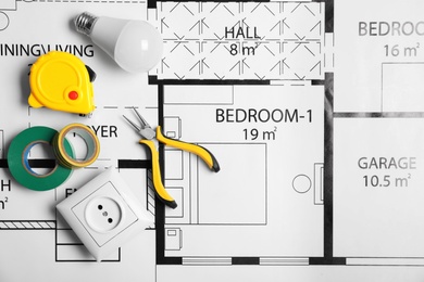 Flat lay composition with electrician's tools on house plan. Space for text