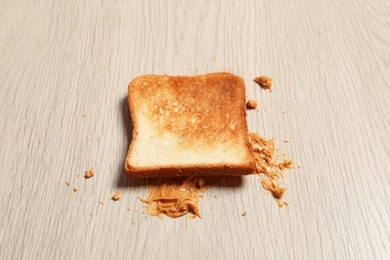 Overturned toast bread with peanut butter on floor