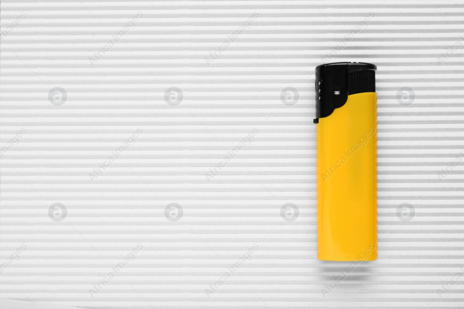 Photo of Stylish small pocket lighter on white corrugated fiberboard, top view. Space for text